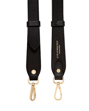 Black adjustable leather bag strap with gold hardware and Strathberry logo.