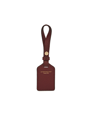 Strathberry oxblood leather tag, rectangular, with strap and gold hardware.
