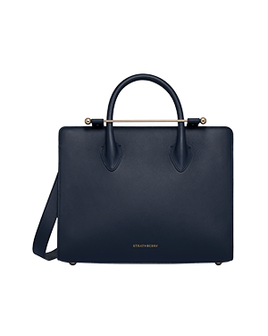Strathberry midi tote in marine blue with top handles, shoulder strap and gold bar fastening.
