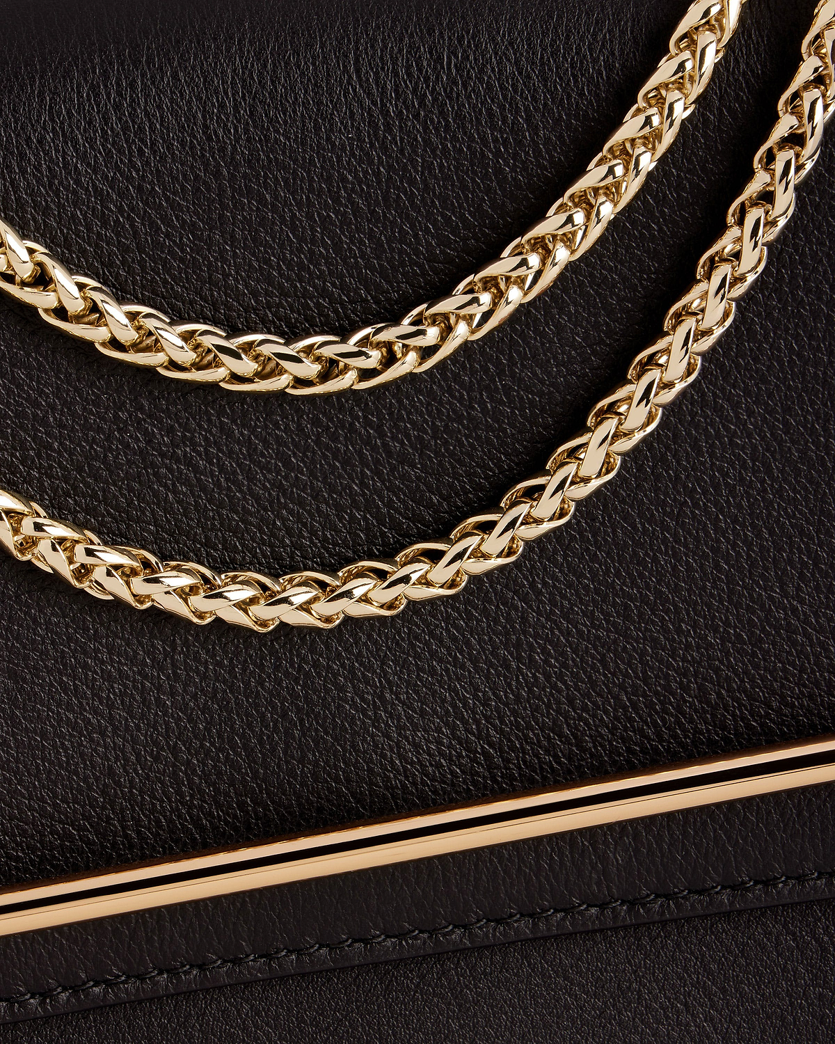 Black textured leather bag with braided gold chain strap and gold bar trim.