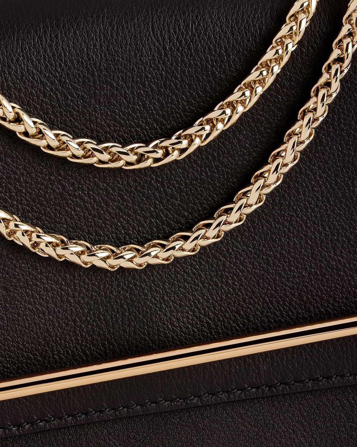 Black textured leather bag with braided gold chain strap and gold bar trim.