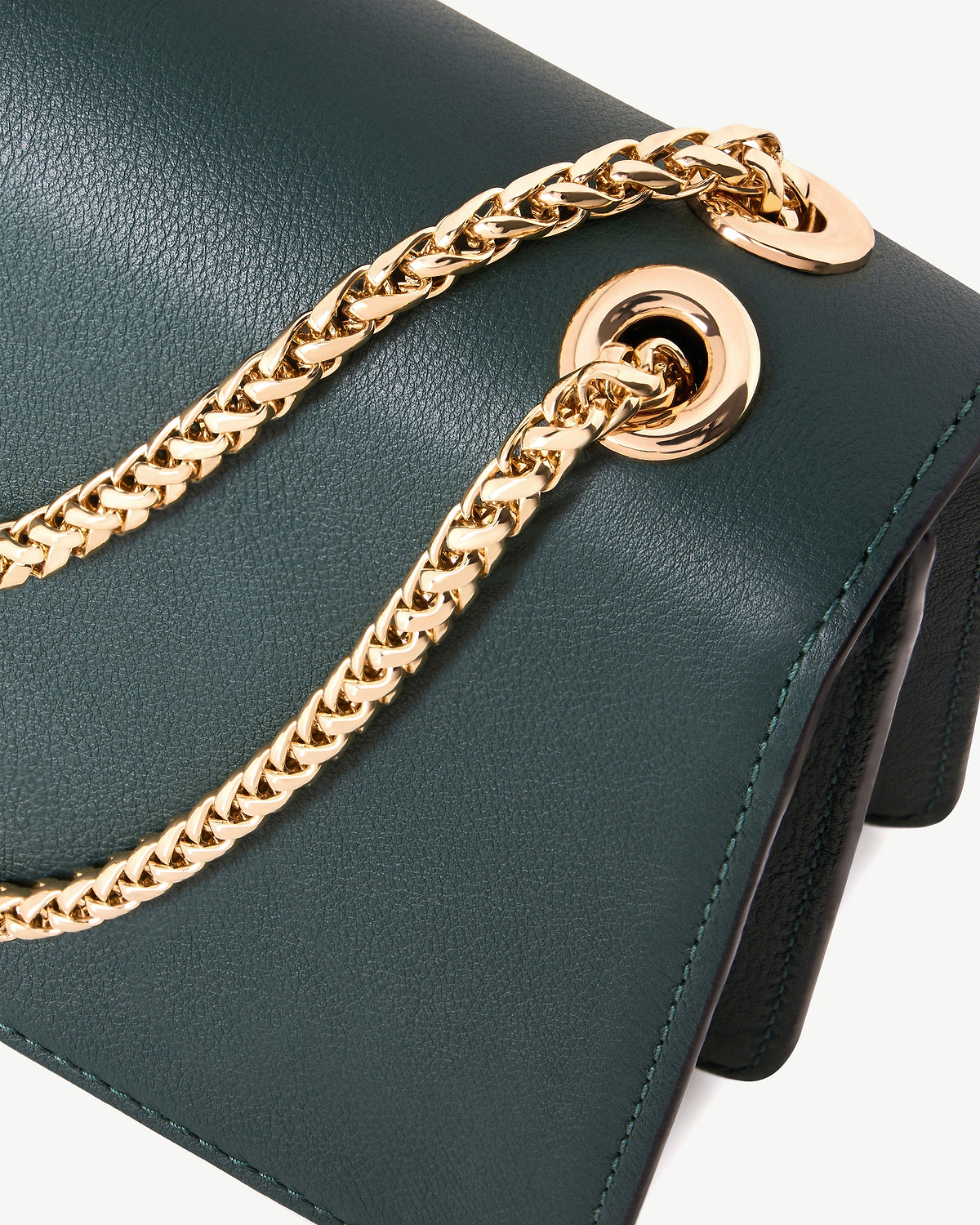 Bottle green East/West Mini leather bag showing gold chain threaded through eyelet.