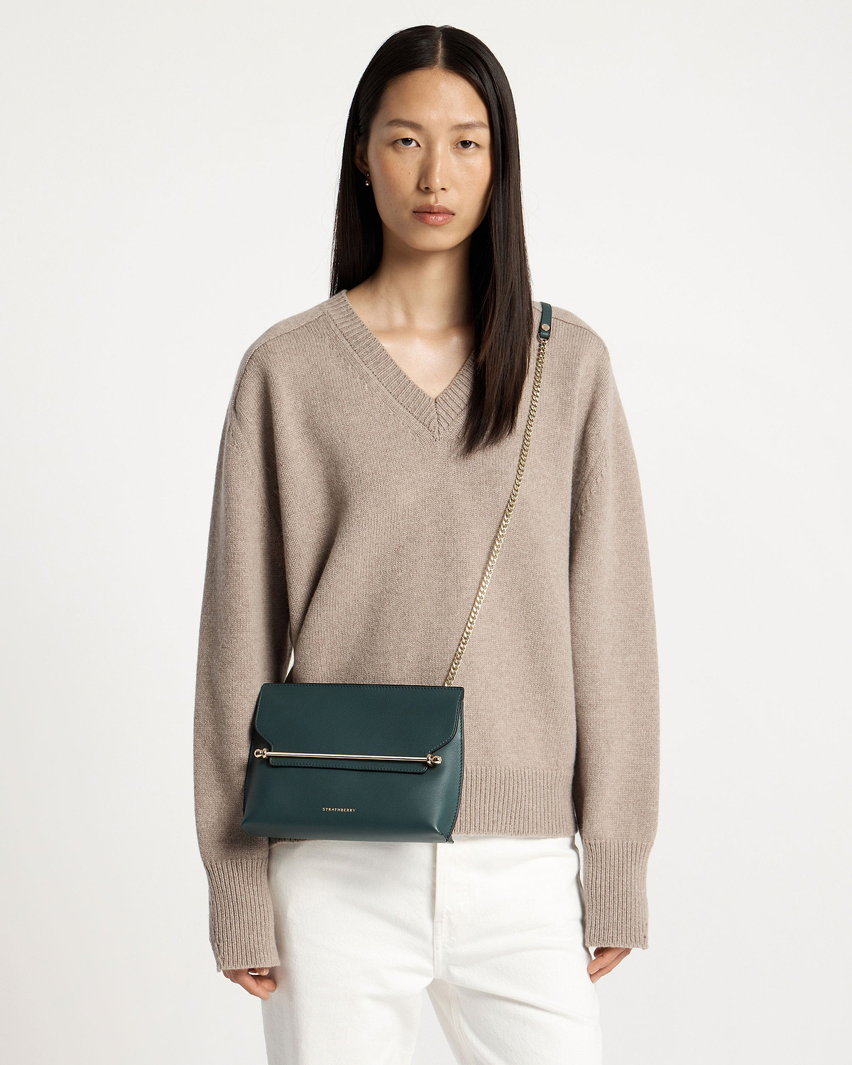 Model wearing Strathberry Stylist bottle green bag with gold chain strap