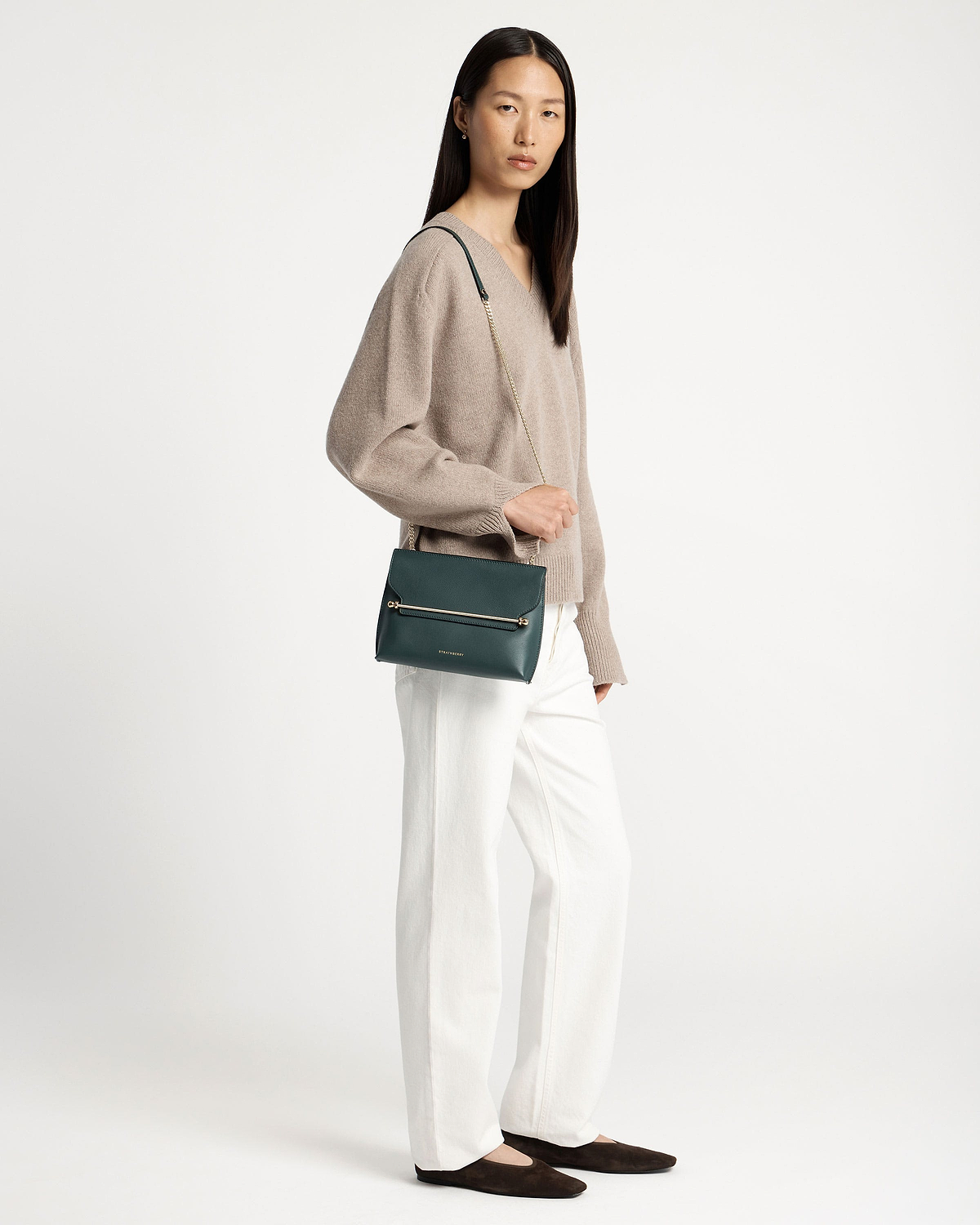 Model wearing bottle green Stylist crossbody bag with gold chain and metal bar.