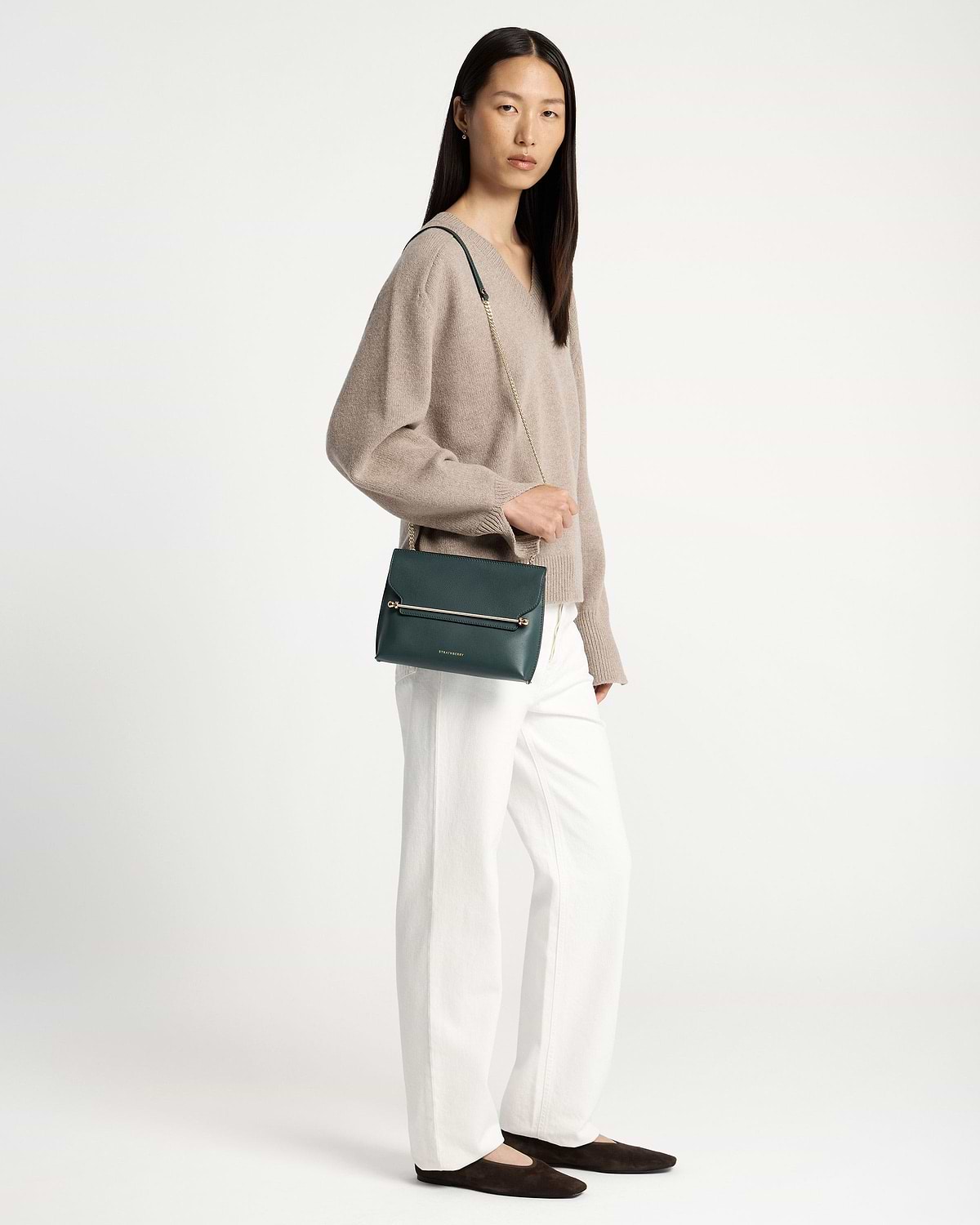 Model wearing bottle green Stylist crossbody bag with gold chain and metal bar.