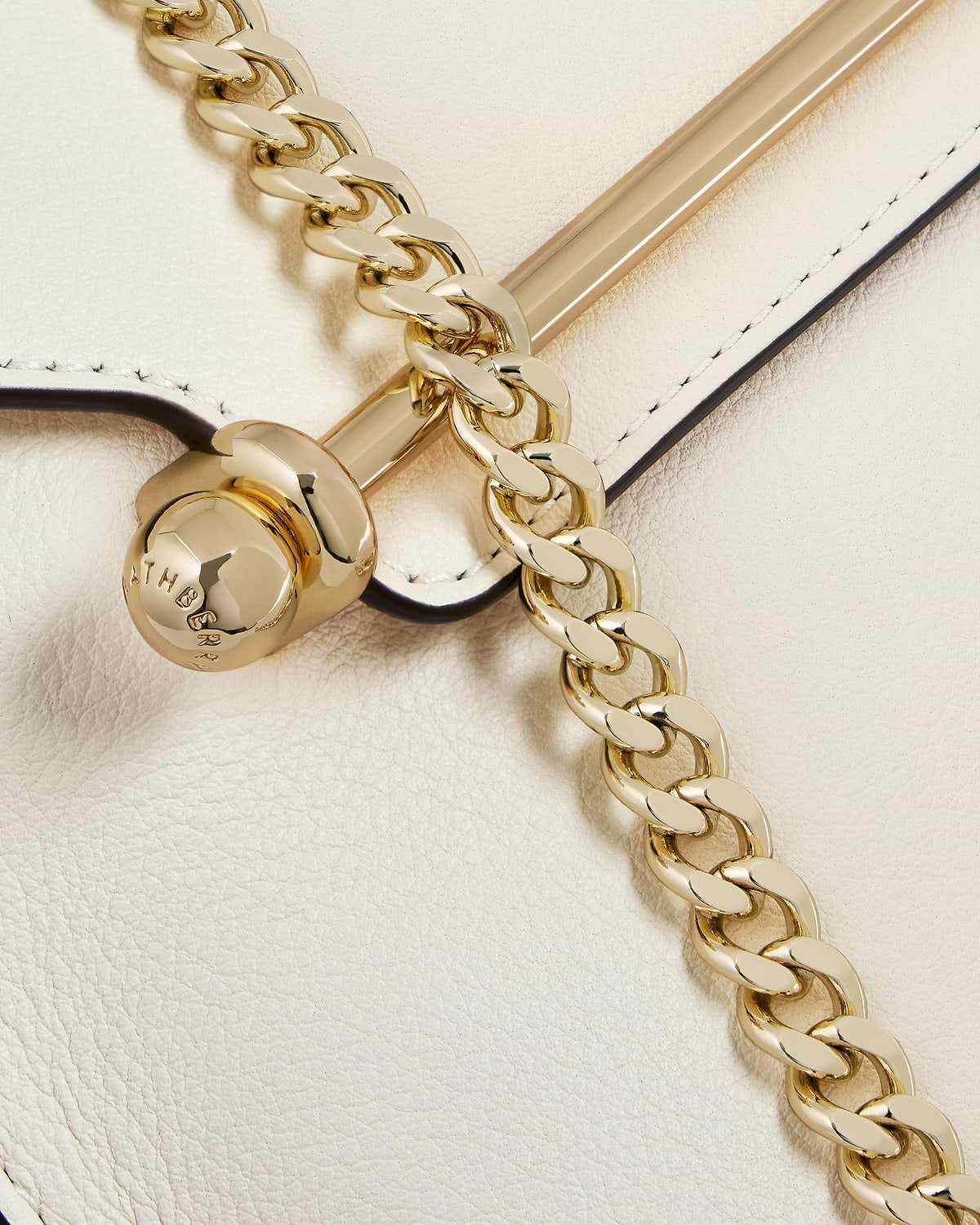 Vanilla leather bag with gold chain and polished bar hardware, stitched edge visible.