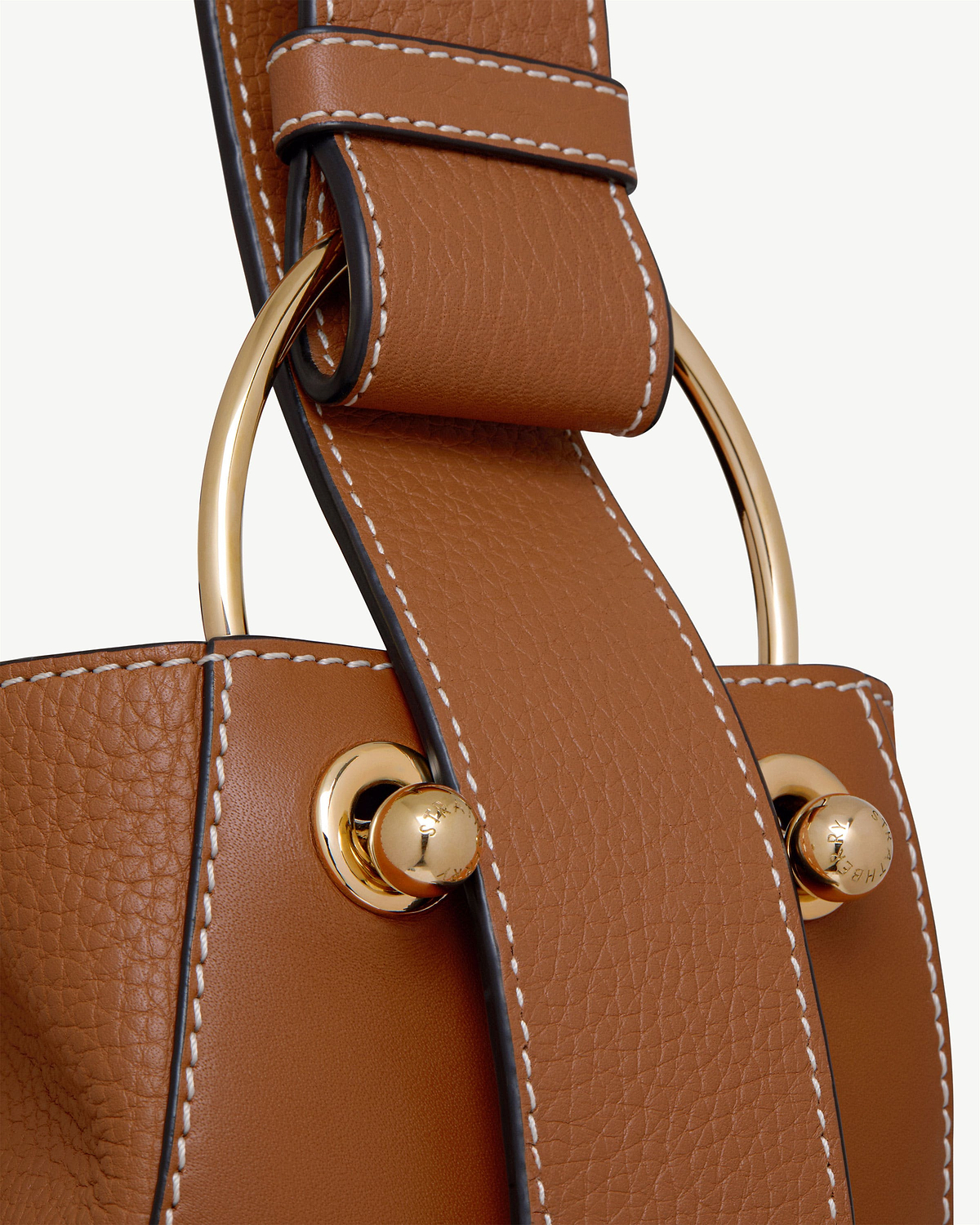 Tan leather bucket bag strap with vanilla contrast stitching and gold metal hardware.