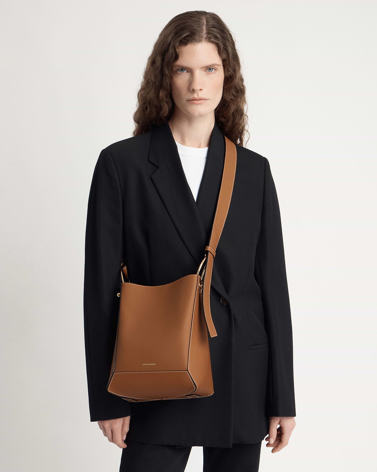 Model wearing tan Strathberry Lana midi bucket bag with vanilla contrast stitching