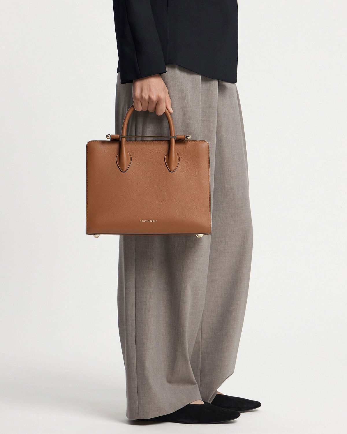 Chestnut Strathberry midi tote held by model cropped below the waist.