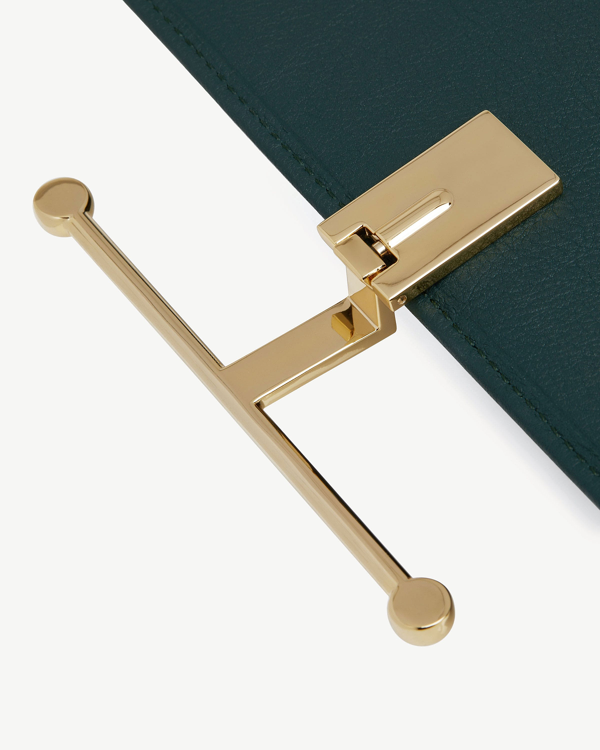 Close-up of bottle green leather wallet showing gold T-bar clasp hardware.
