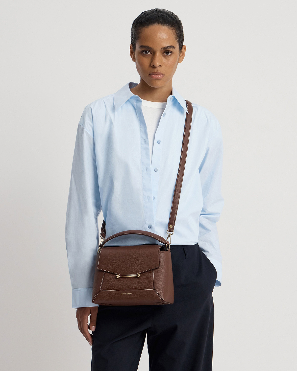 Model wearing chocolate mosaic bag with vanilla stitching and Strathberry logo.