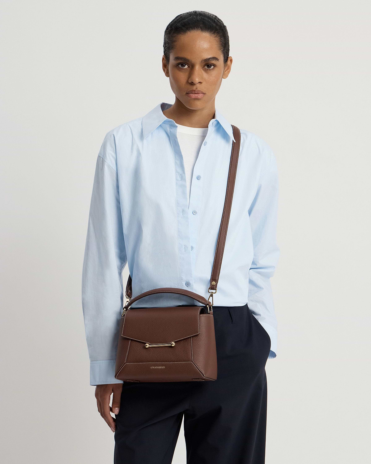 Model wearing chocolate mosaic bag with vanilla stitching and Strathberry logo.