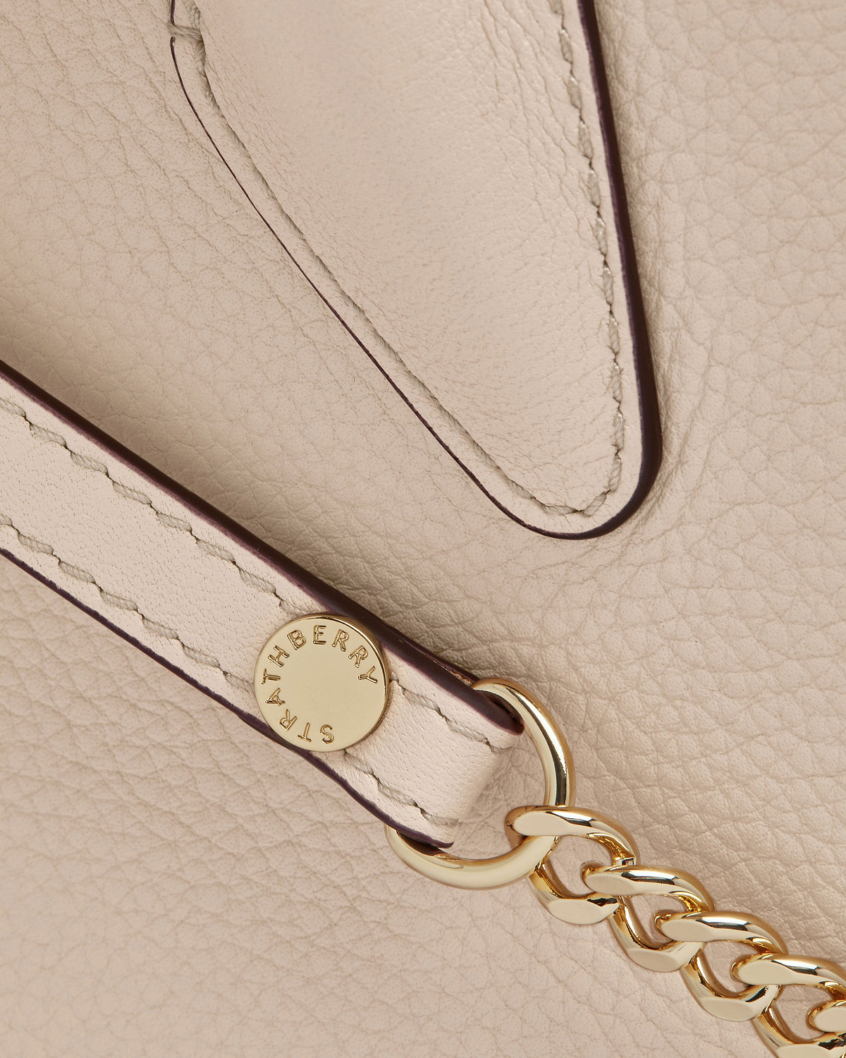 Strathberry mini tote in oat pebbled leather showing strap and gold chain hardware