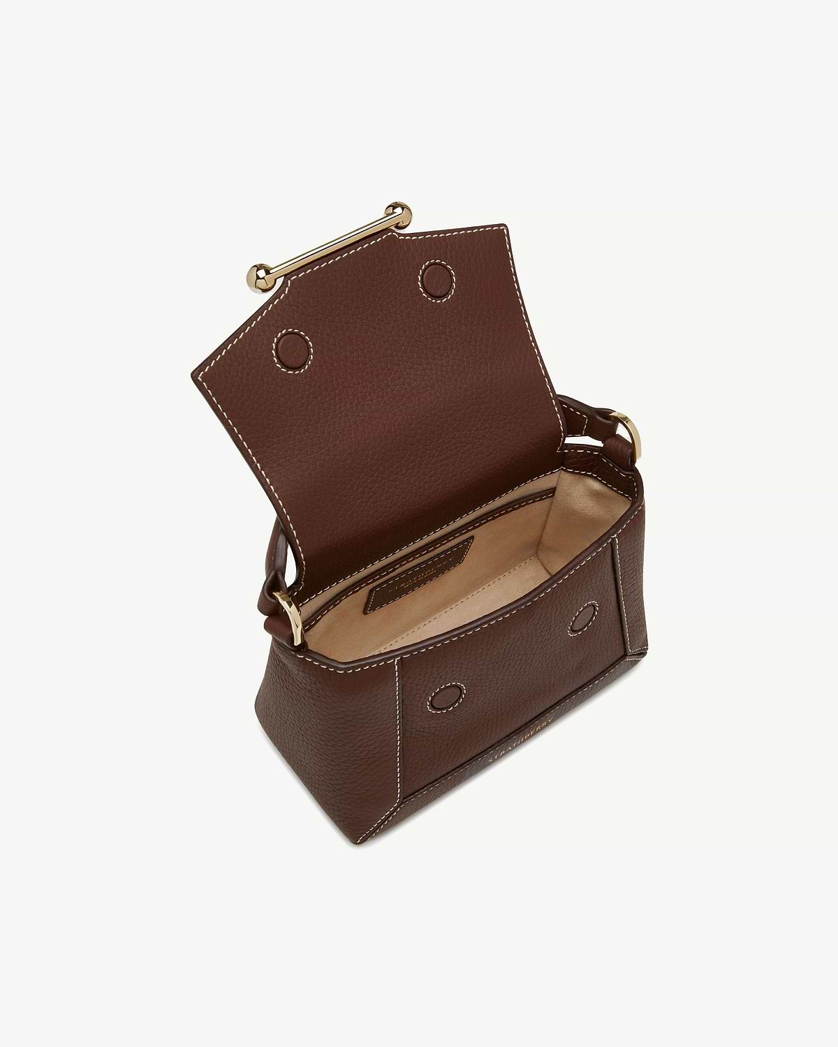 Small chocolate leather bag with vanilla stitching, gold bar closure, flap open showing beige interior.