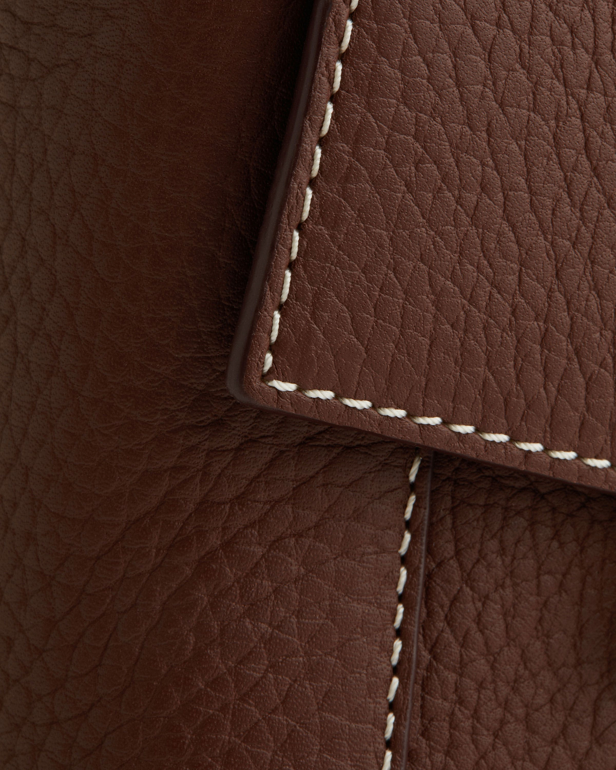 Chocolate brown pebbled leather with vanilla contrast stitching along a folded flap edge.
