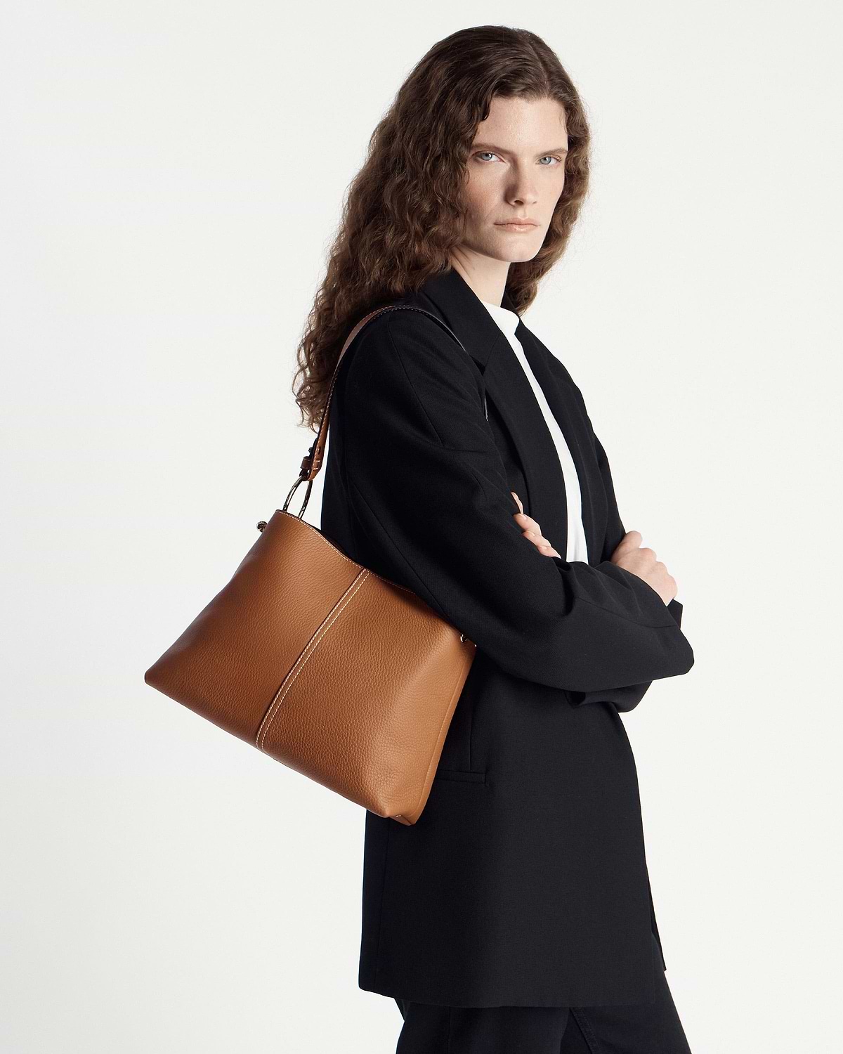 Model wearing a tan leather hobo bag on her shoulder.