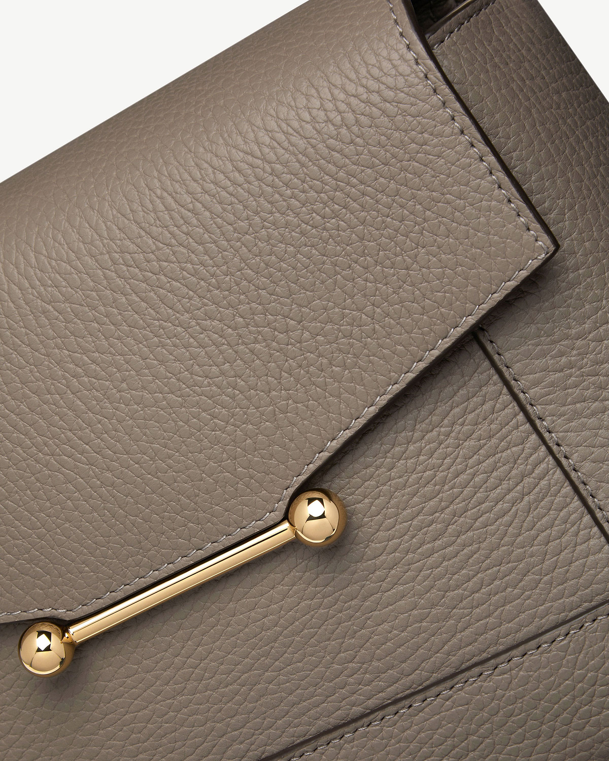 Taupe pebbled leather bag flap with gold bar and spherical end hardware