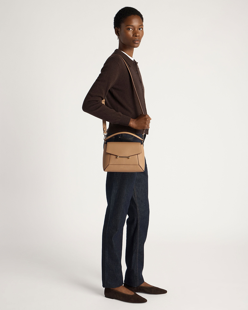 Model wearing a caramel mosaic crossbody bag with brown cardigan and dark jeans.