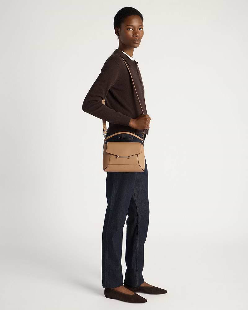 Model wearing a caramel mosaic crossbody bag with brown cardigan and dark jeans.
