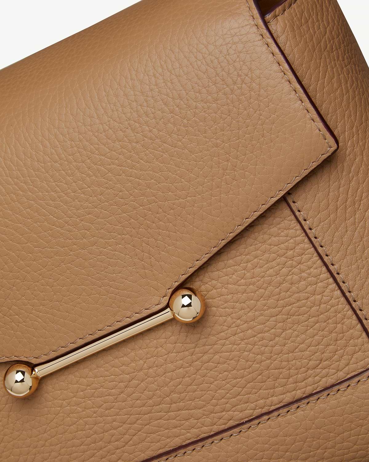 Close-up of caramel pebbled leather mosaic bag showing gold bar hardware.