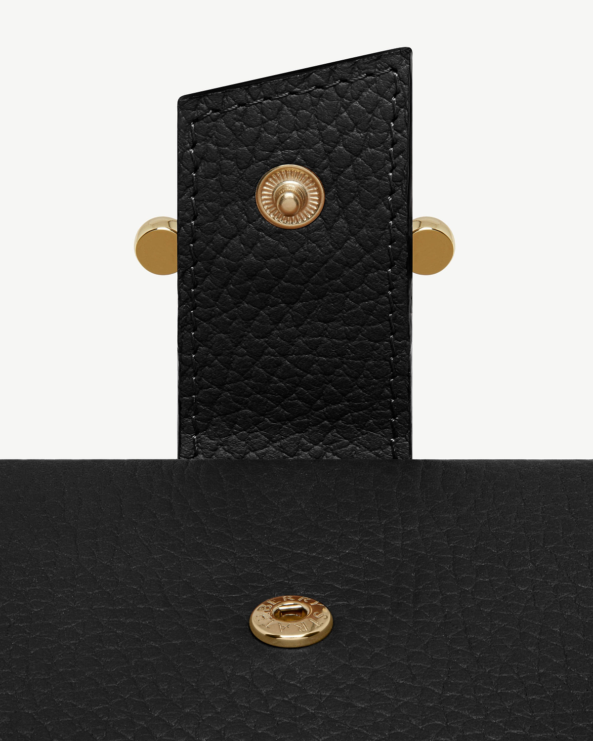 Close-up of black grained leather notebook strap with gold press stud