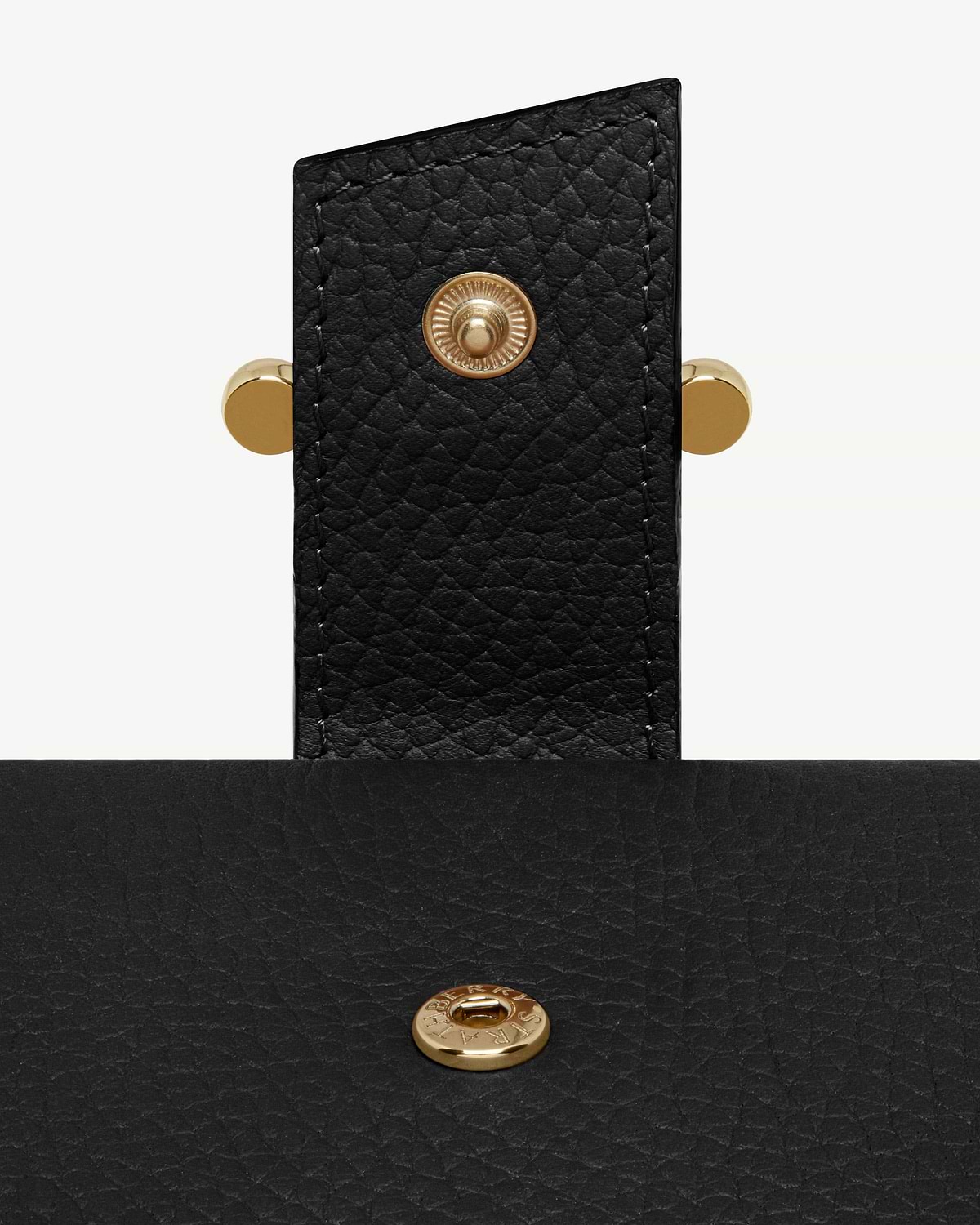 Close-up of black grained leather notebook strap with gold press stud
