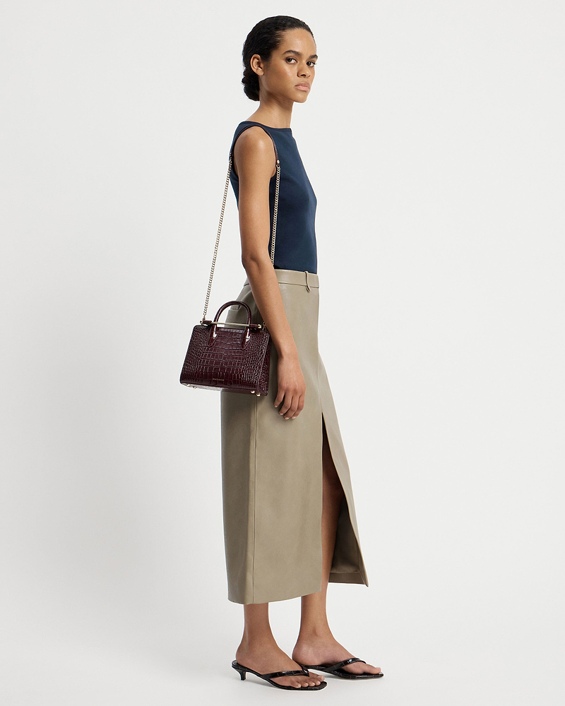 Model wearing a croc mini tote with chain strap over her shoulder.