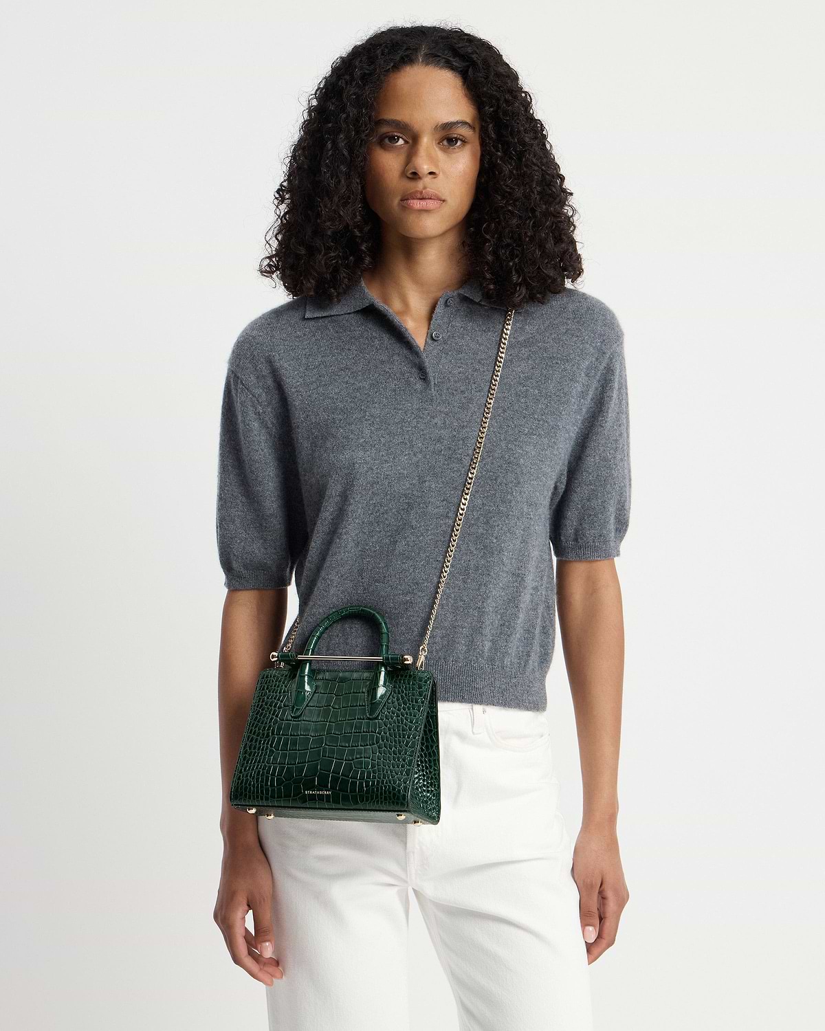Model wearing grey top with Strathberry green croc mini tote and chain strap.