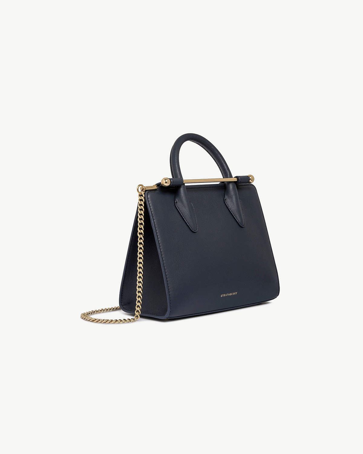 Marine blue Strathberry mini tote with top handle, gold bar and chain strap.