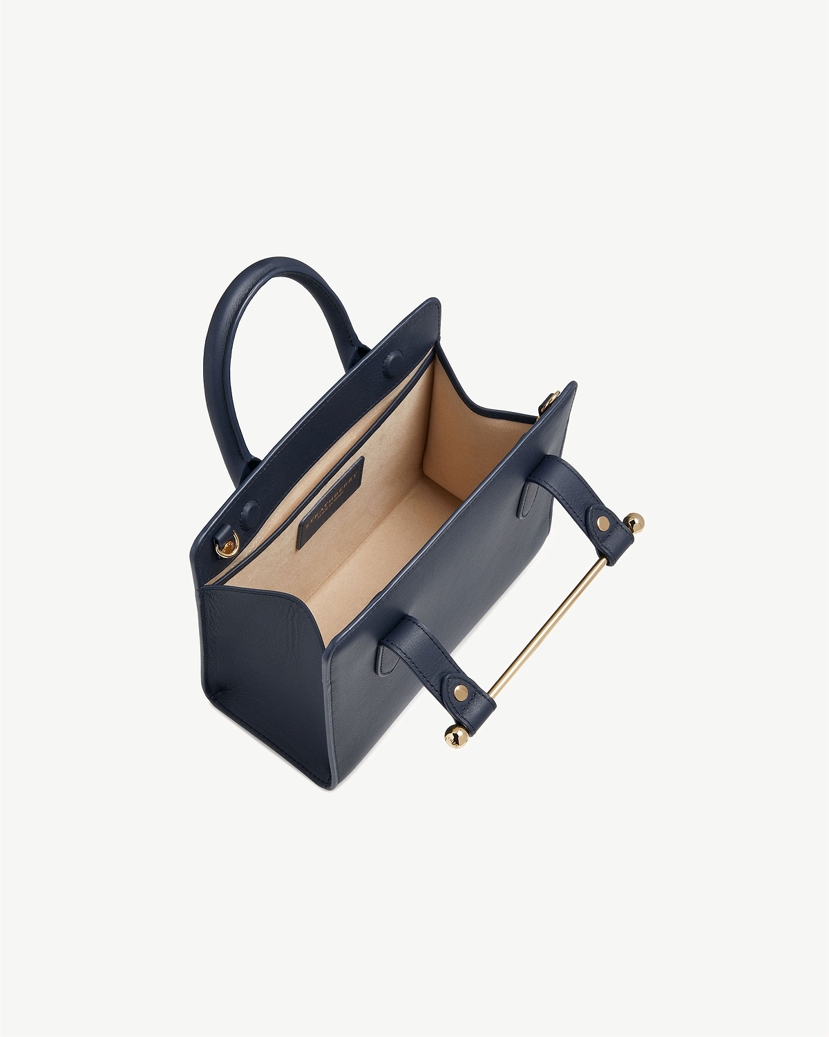 Marine blue mini tote with beige interior and gold bar handle, top view.