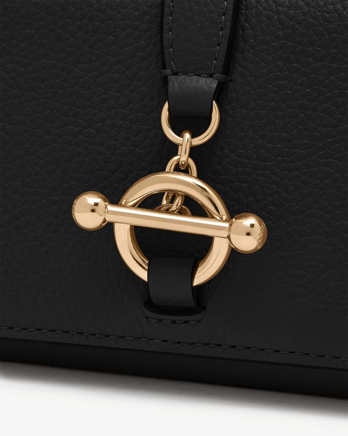 Black pebbled leather wallet with round gold toggle clasp detail.