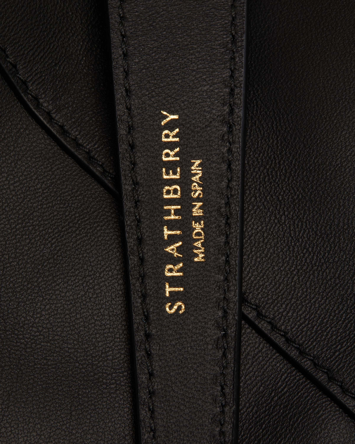 Black leather strap stamped Strathberry and 'Made in Spain' in gold.