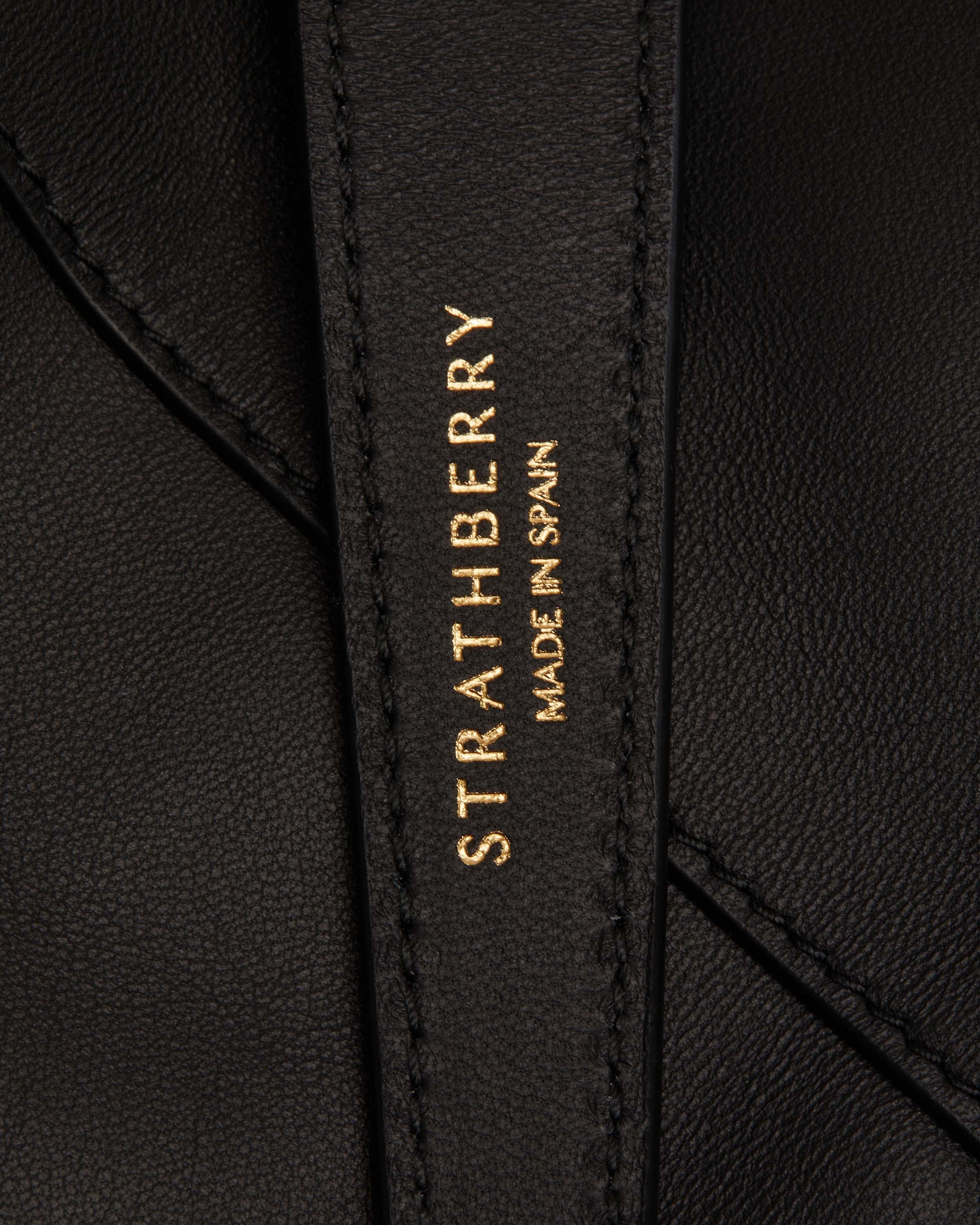 Black leather strap stamped Strathberry and 'Made in Spain' in gold.