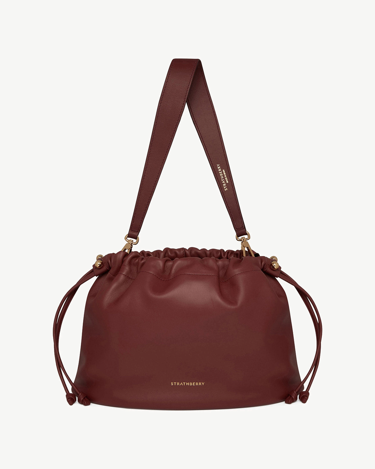 Oxblood Charlotte Midi drawstring bag with wide strap and gold Strathberry logo.