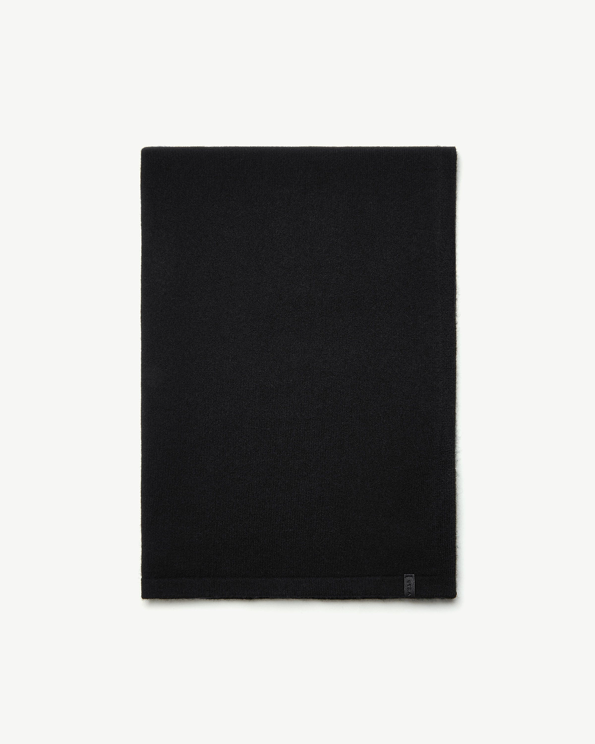 Black cashmere travel wrap folded flat on white background with small tag at hem.