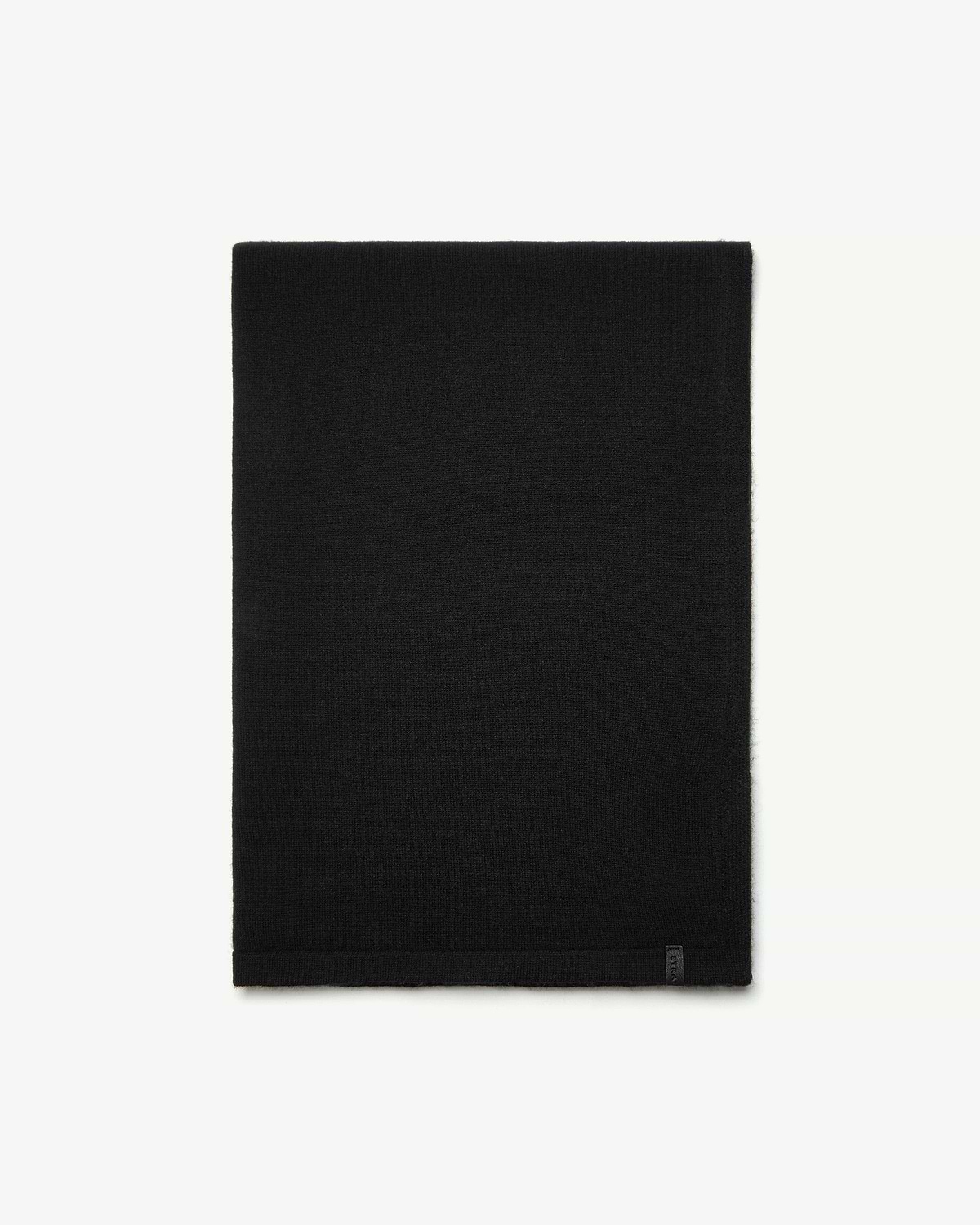 Black cashmere travel wrap folded flat on white background with small tag at hem.