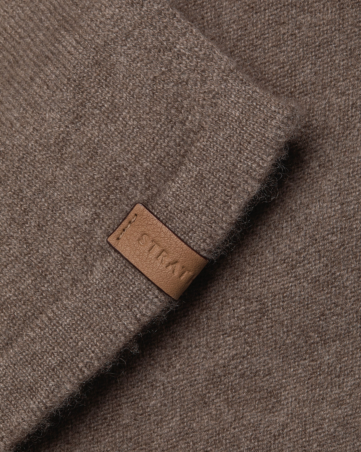 Otter brown cashmere travel wrap, close-up of knitted texture and leather tag