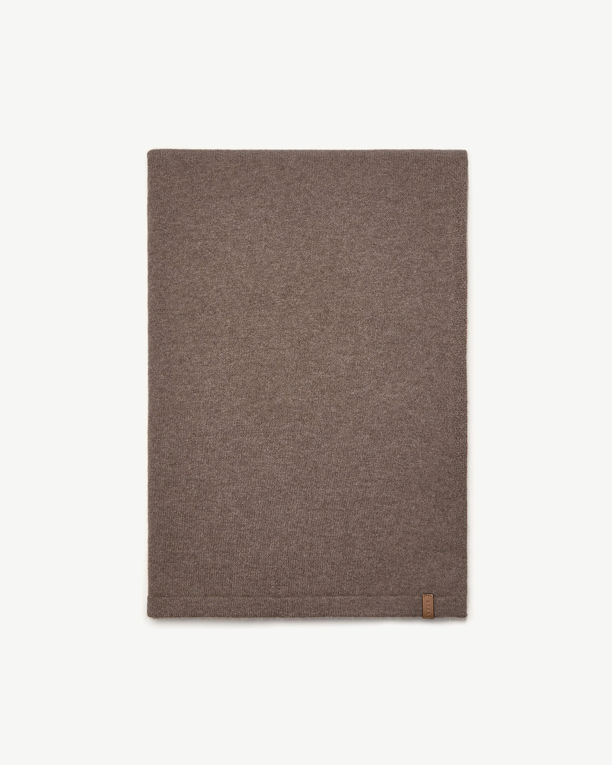Otter-coloured cashmere travel wrap laid flat on white background with small leather tag.