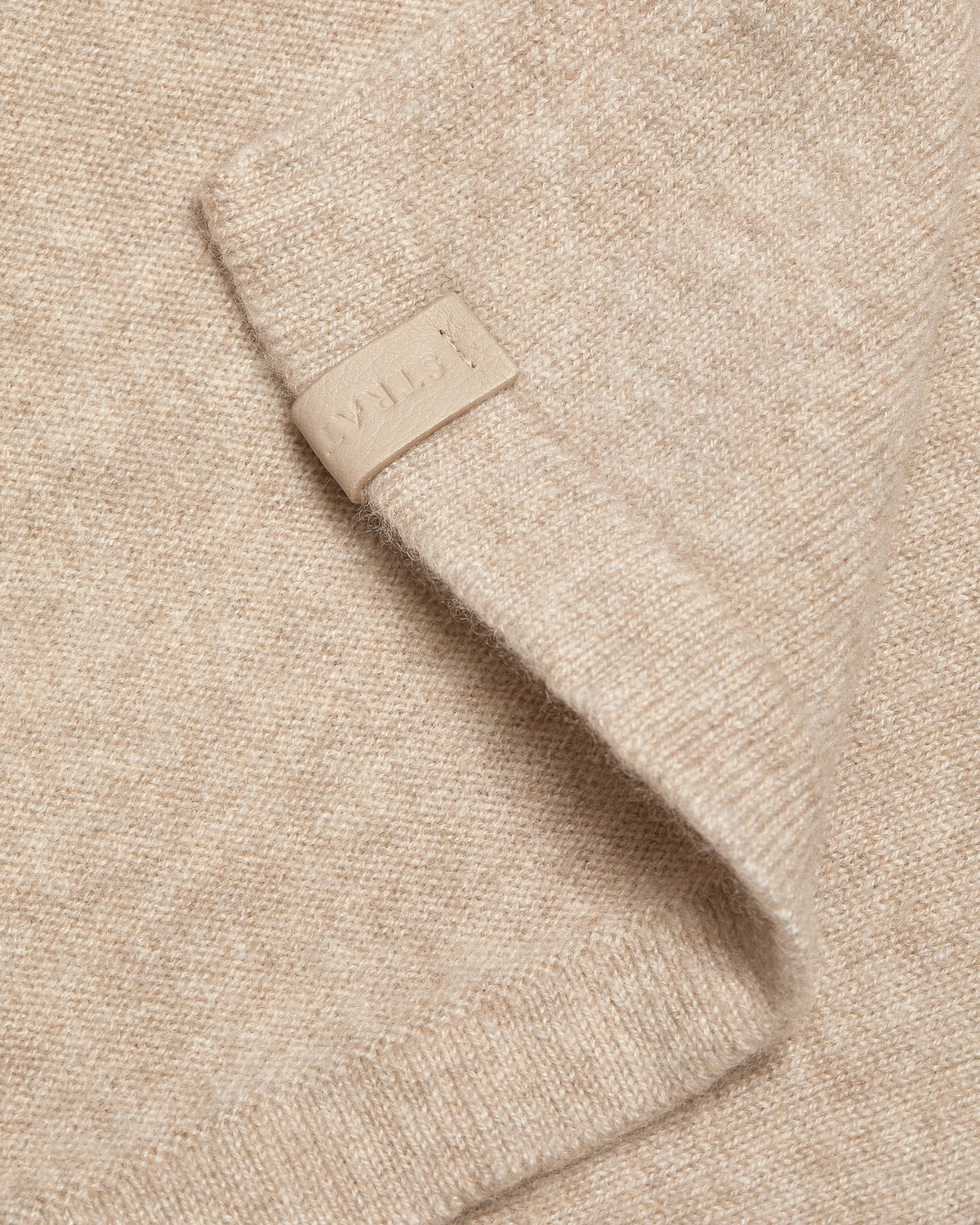 Oat cashmere travel wrap detail with embossed Strathberry leather tab.