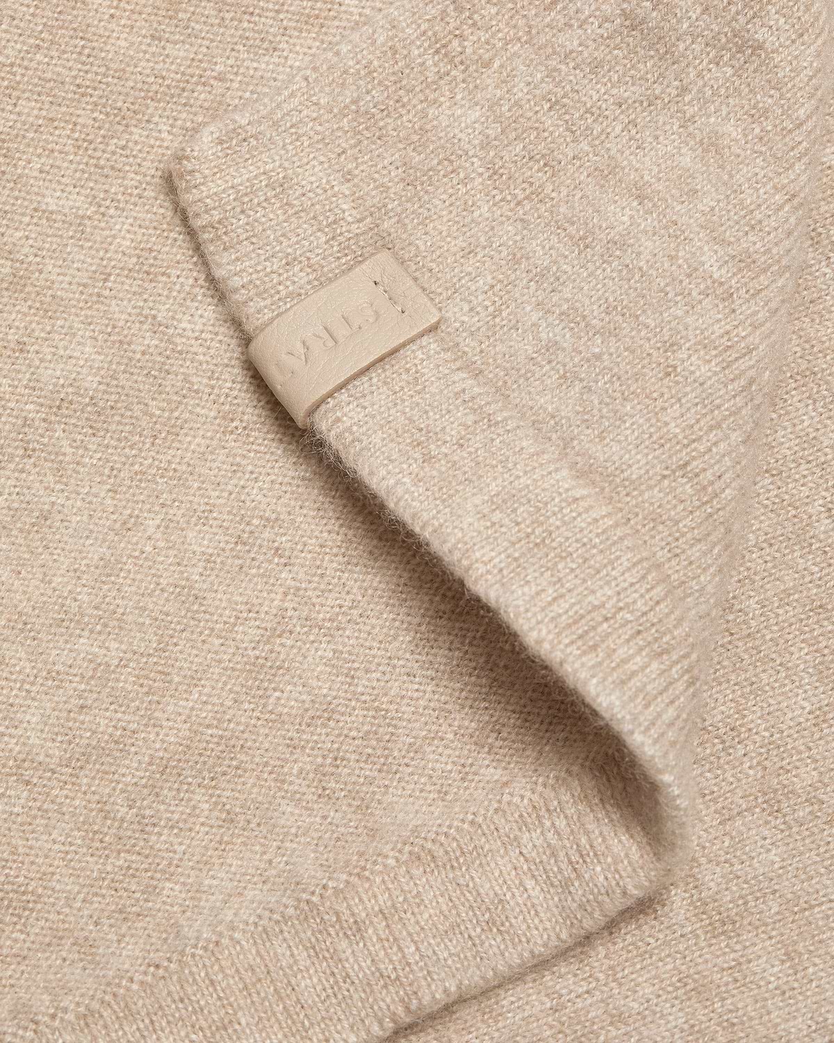 Oat cashmere travel wrap detail with embossed Strathberry leather tab.