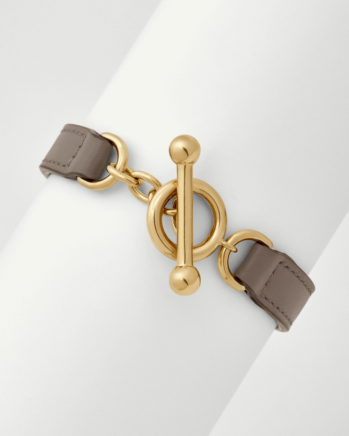 Taupe leather kite bracelet showing gold toggle fastening and linked rings