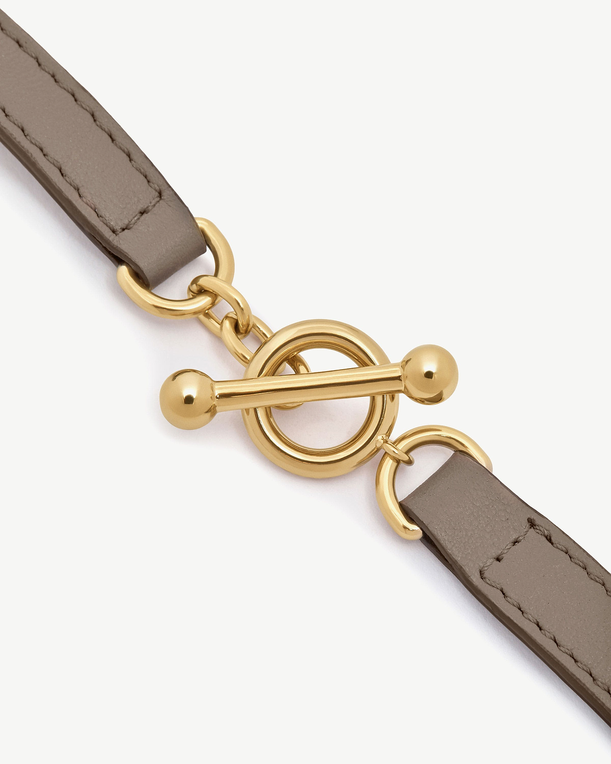 Taupe leather bracelet strap with gold toggle clasp and metal rings.