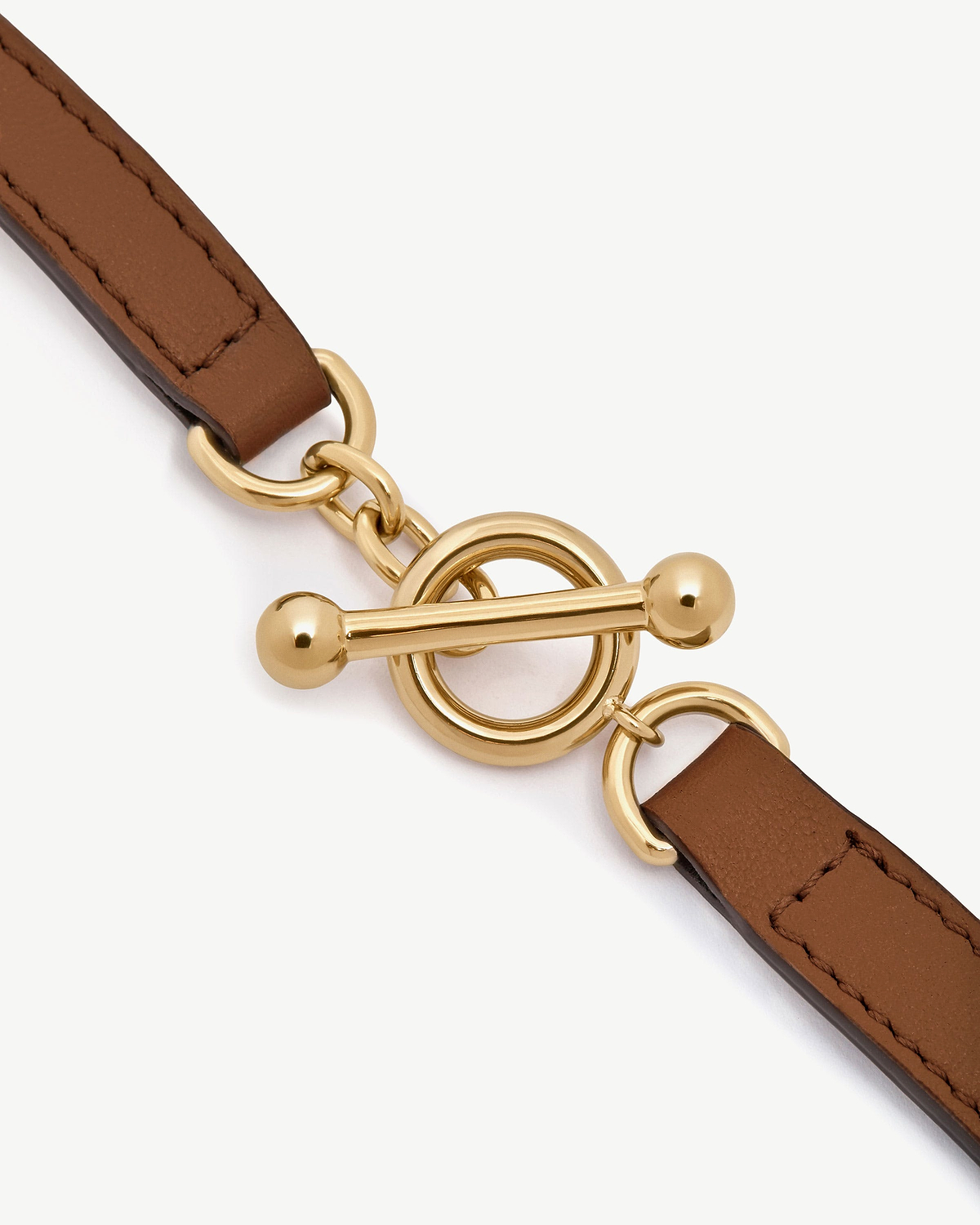 Tan leather bracelet strap with gold toggle clasp and circular links.