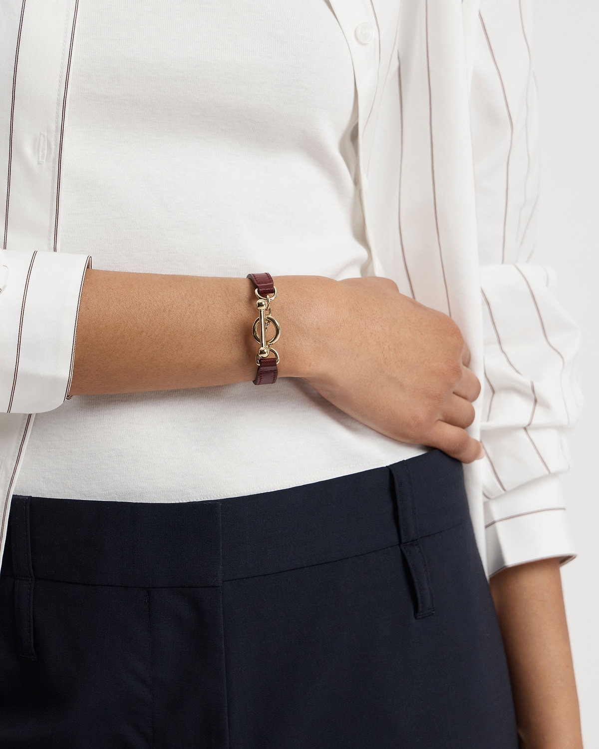Oxblood leather Kite bracelet with gold hardware on model's wrist.