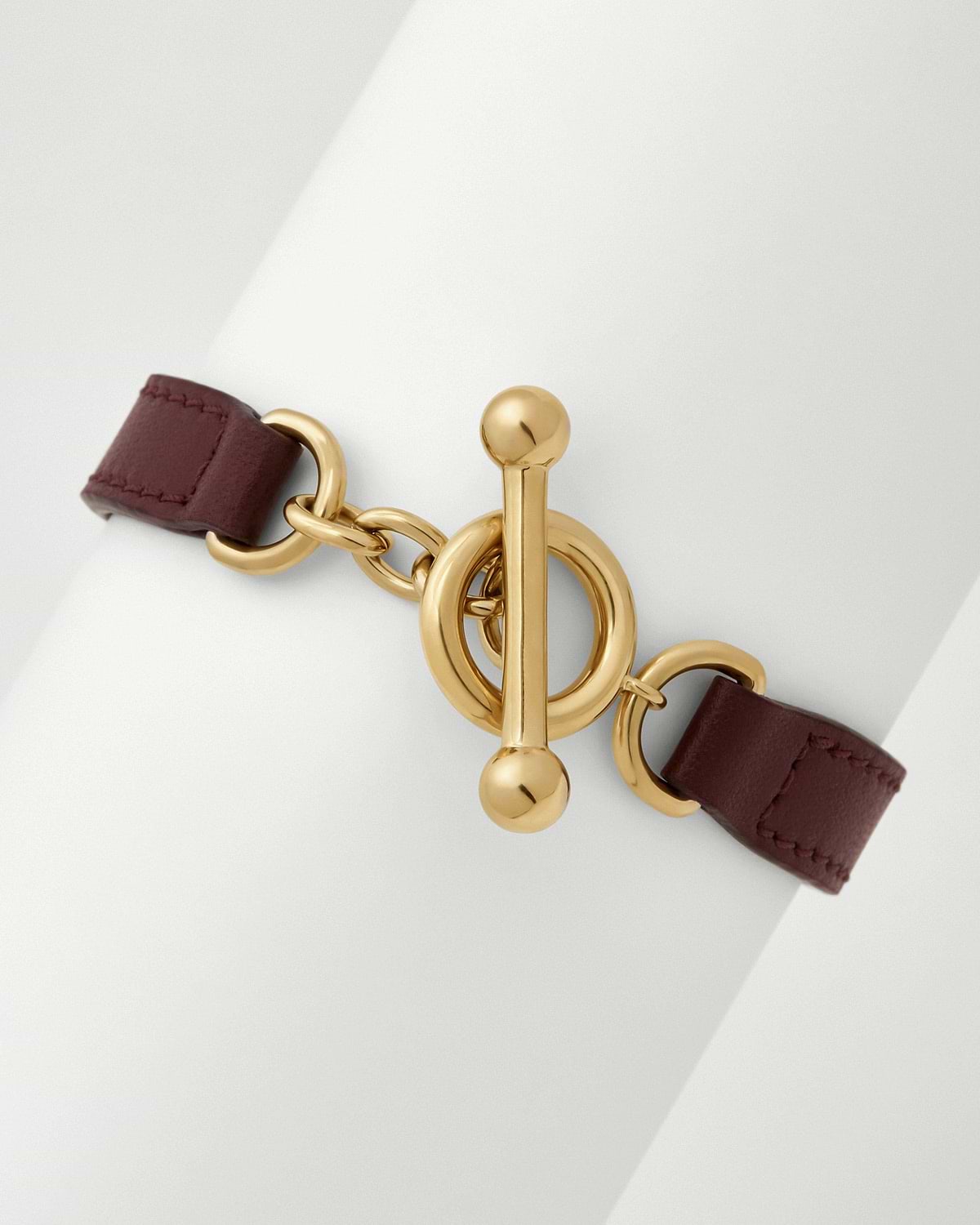 Oxblood leather kite bracelet with gold toggle clasp on white background