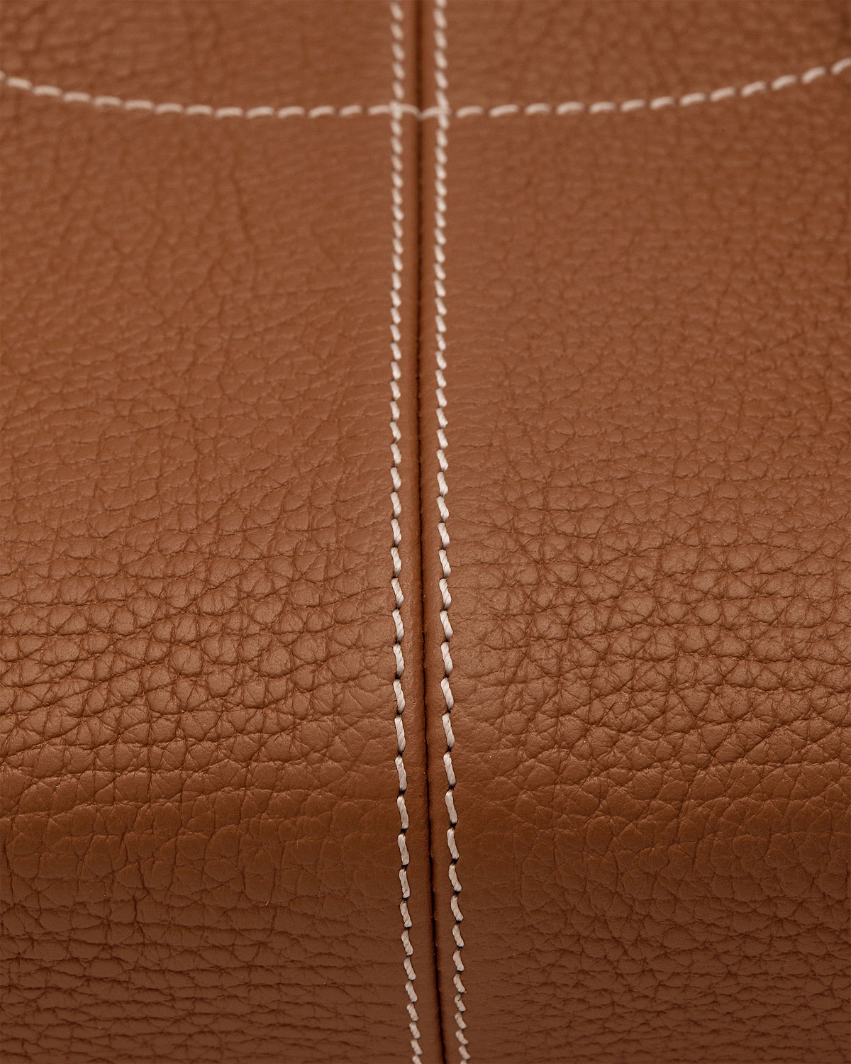 Close-up of tan pebbled leather with central seam and double white stitching