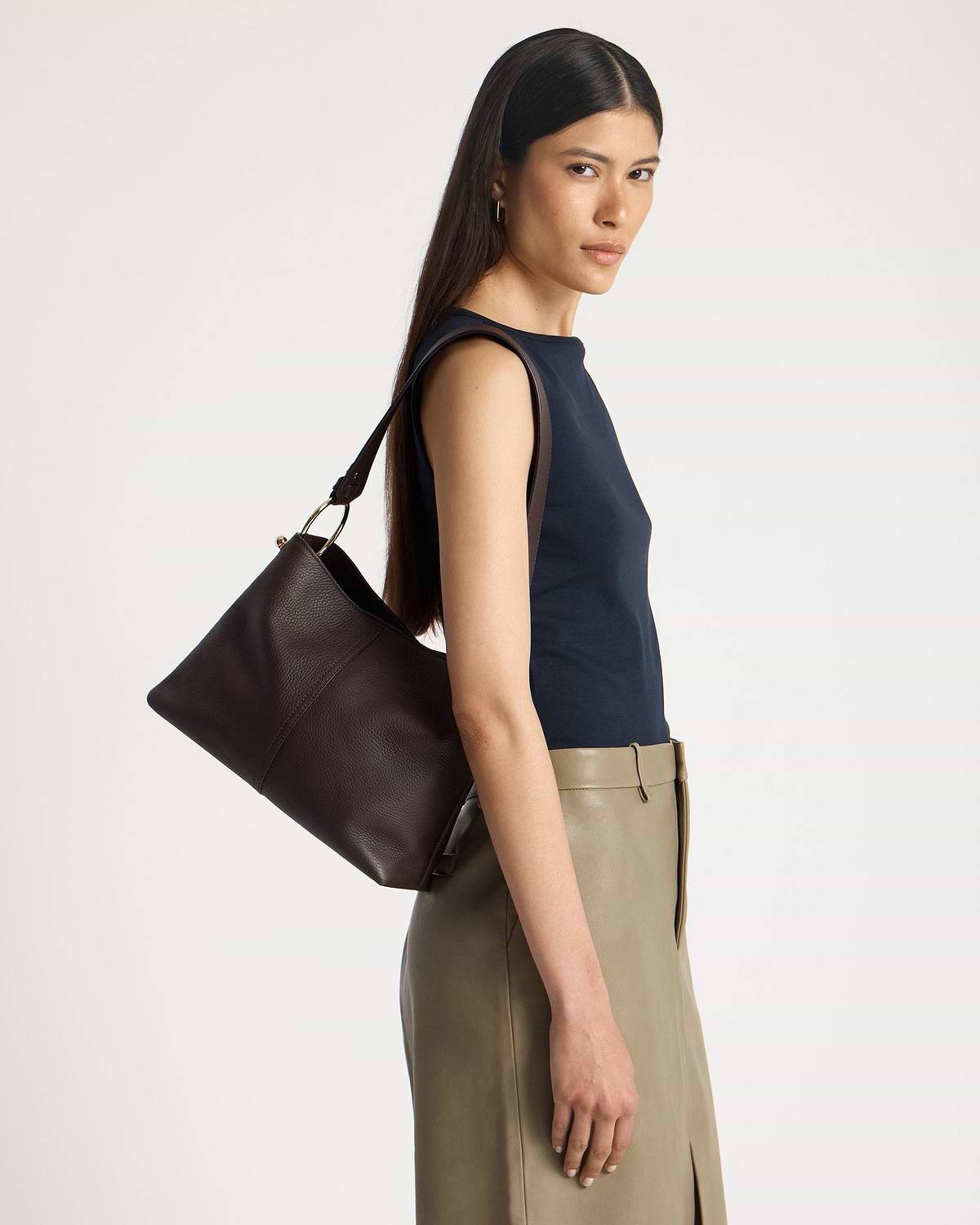 Model wearing a navy sleeveless top and olive skirt, carrying an espresso leather hobo bag.