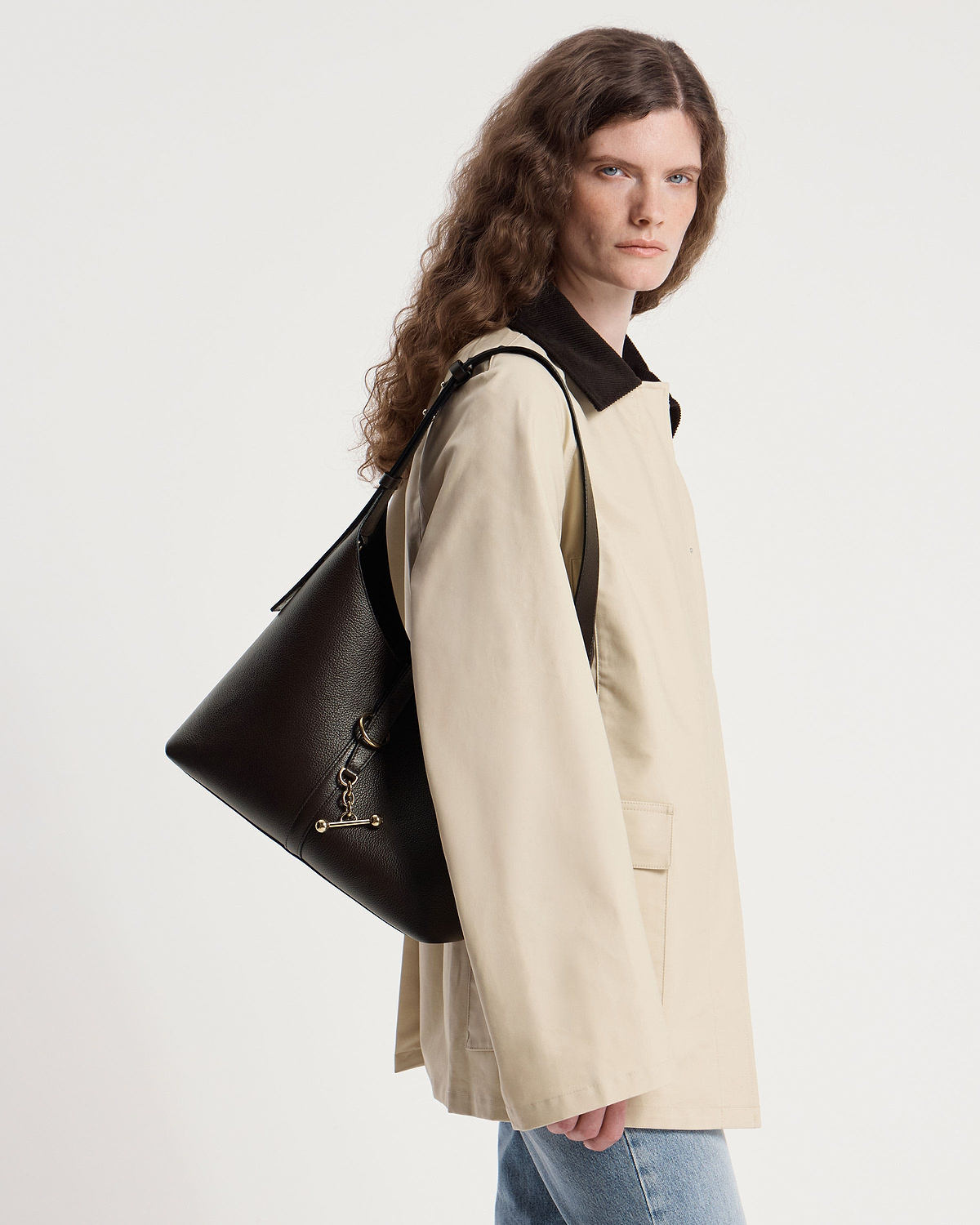 Model wearing a beige coat carrying an espresso leather Kite Hobo bag.