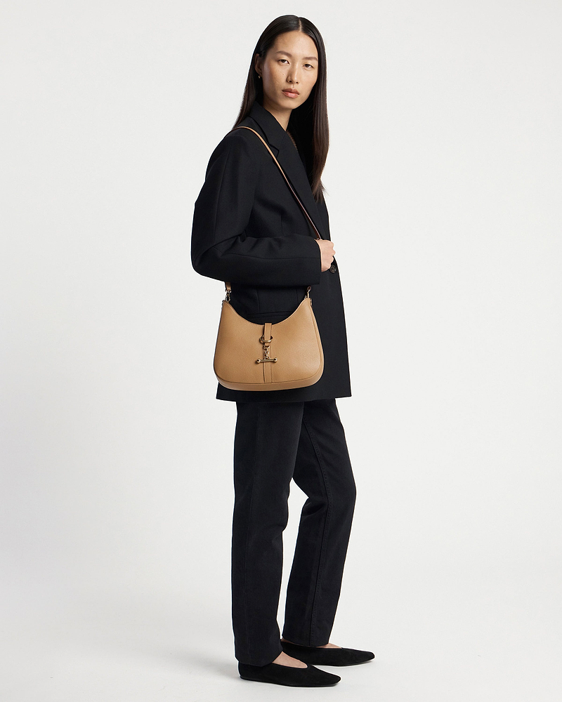 Model wearing caramel kite sling bag with shoulder strap and black blazer.