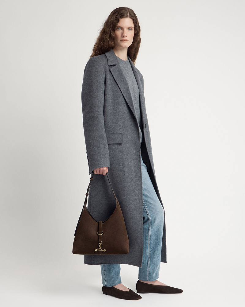 Model wearing grey coat and jeans holding chocolate suede Kite Hobo bag.